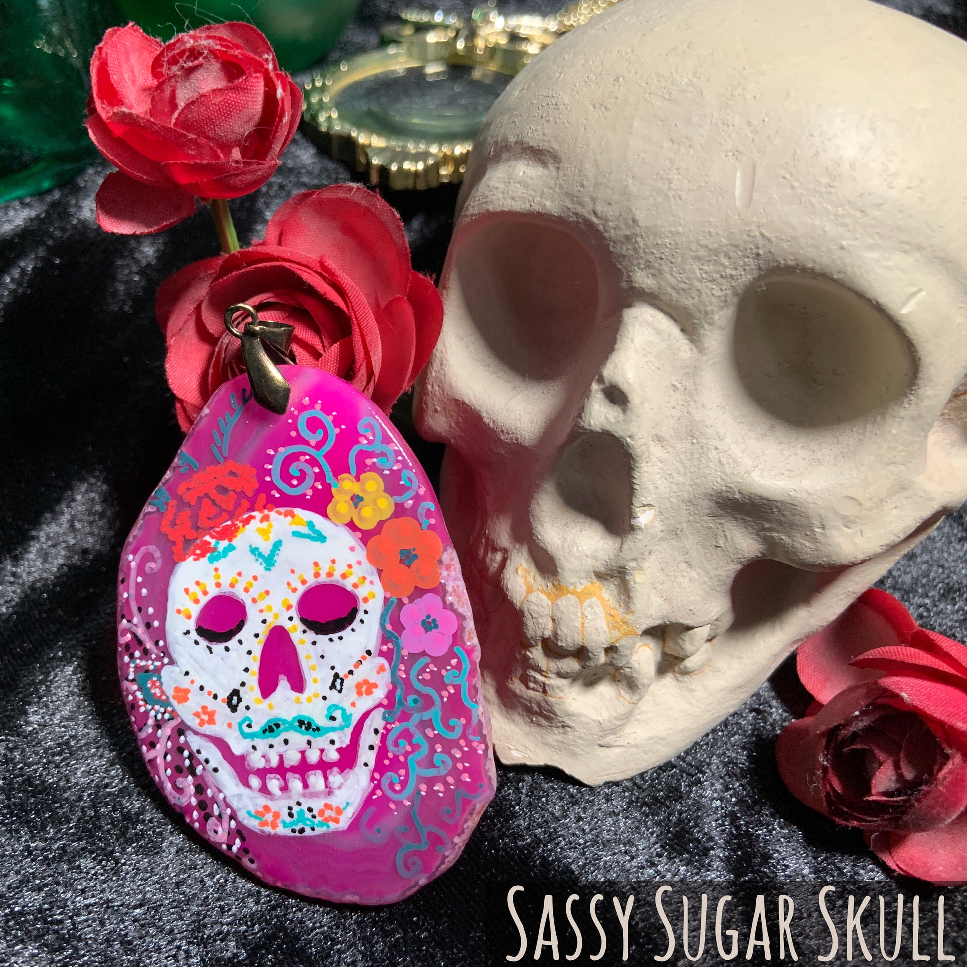 A flamboyantly painted sugar skull. A twirled mustache in turquoise, a beaded red cap with teal feathers, and multiple colors of flowers, ribbons, and beads.